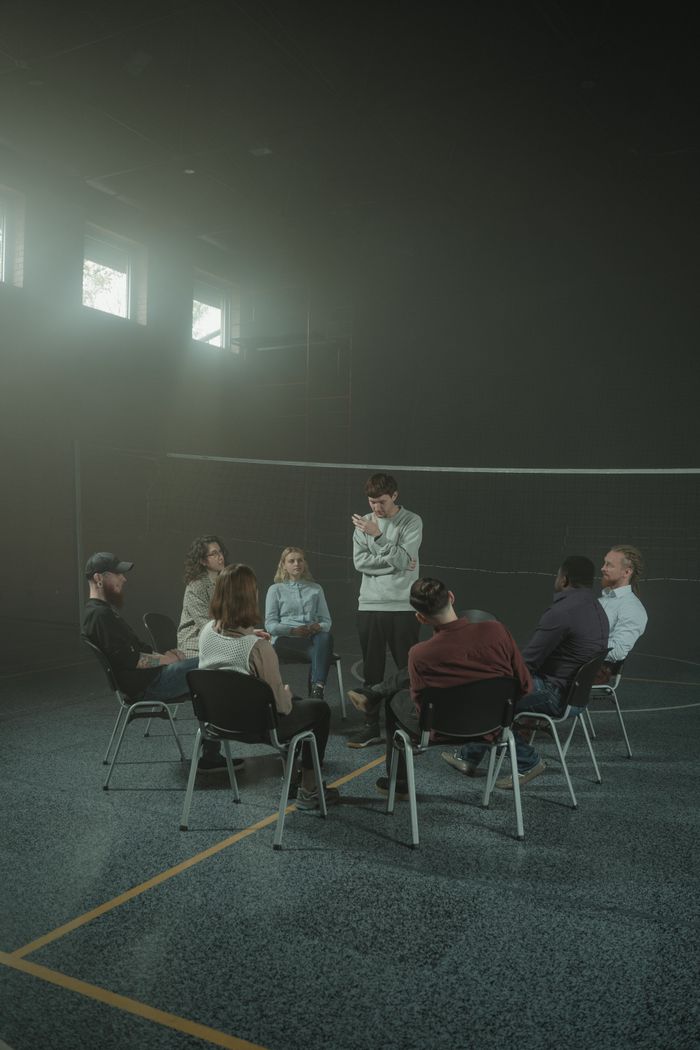 A group of adults engaged in a therapy session within a calm, smoky indoor environment.