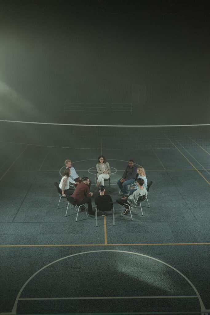 The Art of Drawing Readers In: Your attractive post title goes here Multicultural support group sitting in a circle in a gym, discussing personal issues.