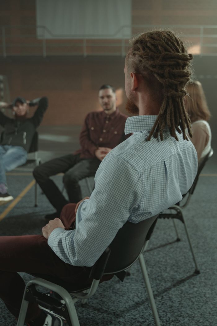 A diverse group of adults engaging in a support therapy session in an indoor setting.