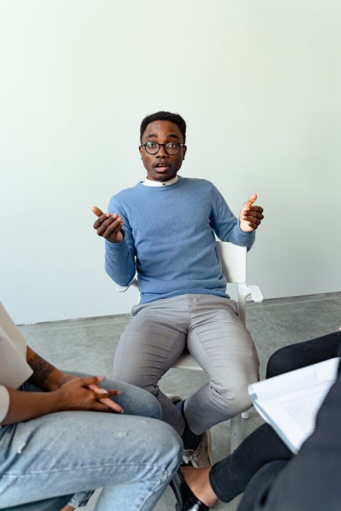 Mastering the First Impression: Your intriguing post title goes here Man in blue sweater leading a group therapy discussion indoors.
